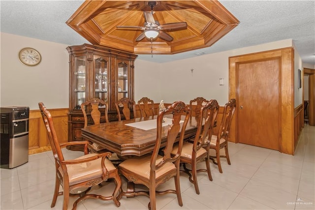 dining area with a raised ceiling, ceiling fan, and a textured ceiling