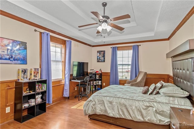 bedroom featuring light wood-type flooring, multiple windows, ornamental molding, and ceiling fan