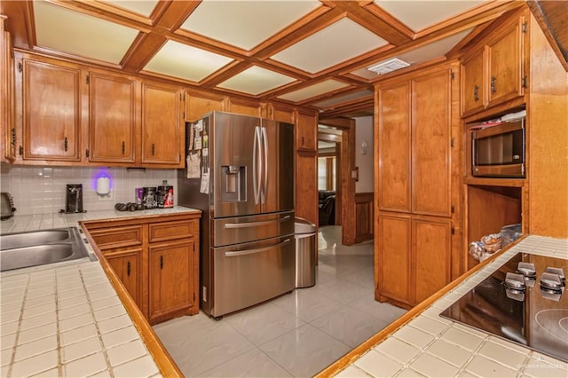 kitchen featuring tile countertops, backsplash, coffered ceiling, sink, and stainless steel appliances