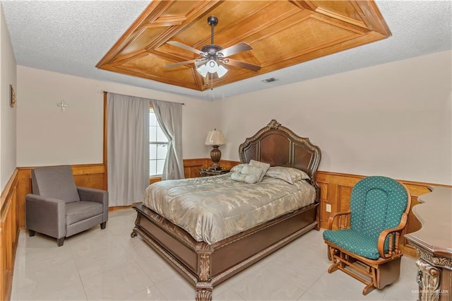 bedroom featuring ceiling fan, wood walls, and a textured ceiling