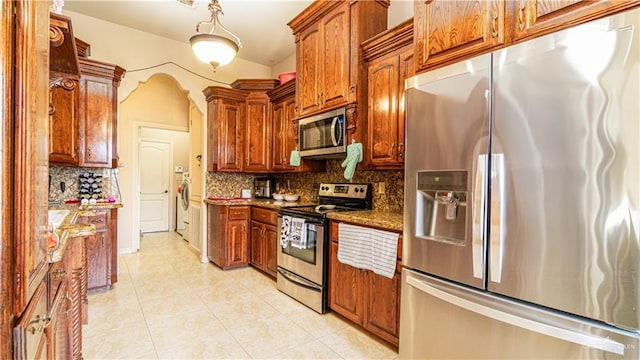 2904 Victoria St, Hidalgo, TX 78557 - kitchen with appliances with stainless steel finishes, backsplash, light tile patterned floors, dark stone countertops, and washer / clothes dryer