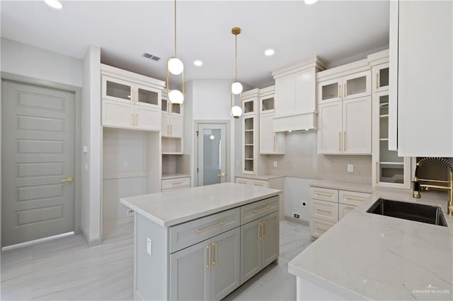 kitchen with visible vents, recessed lighting, light stone counters, a sink, and hanging light fixtures