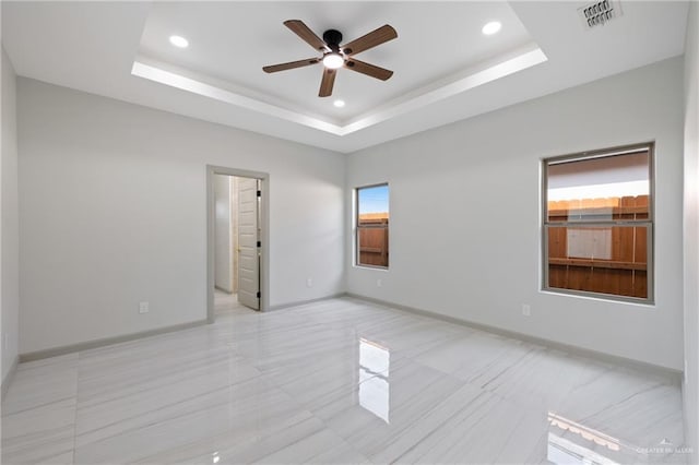empty room featuring a raised ceiling, ceiling fan, recessed lighting, and visible vents
