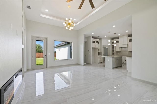 unfurnished living room with visible vents, recessed lighting, baseboards, and ceiling fan with notable chandelier