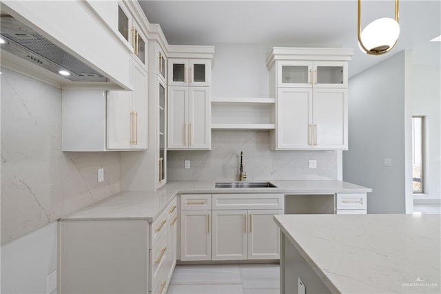 kitchen featuring open shelves, decorative backsplash, premium range hood, light stone counters, and a sink