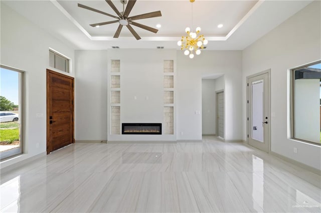 unfurnished living room featuring recessed lighting, a glass covered fireplace, ceiling fan with notable chandelier, and a tray ceiling