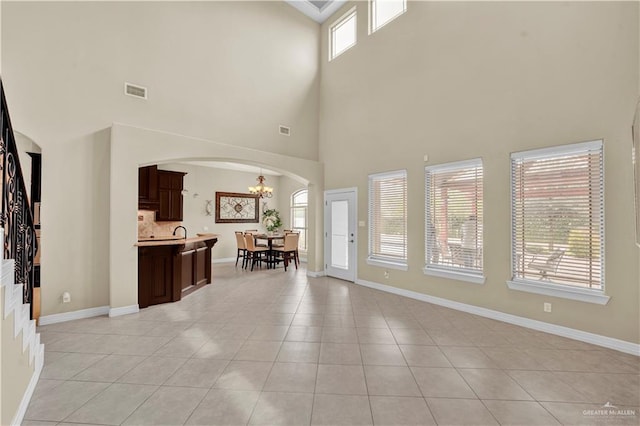 entryway featuring arched walkways, a chandelier, baseboards, and light tile patterned flooring