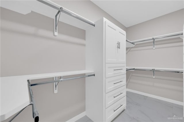 walk in closet featuring marble finish floor