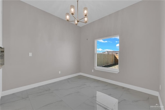 unfurnished room with a chandelier, marble finish floor, and baseboards