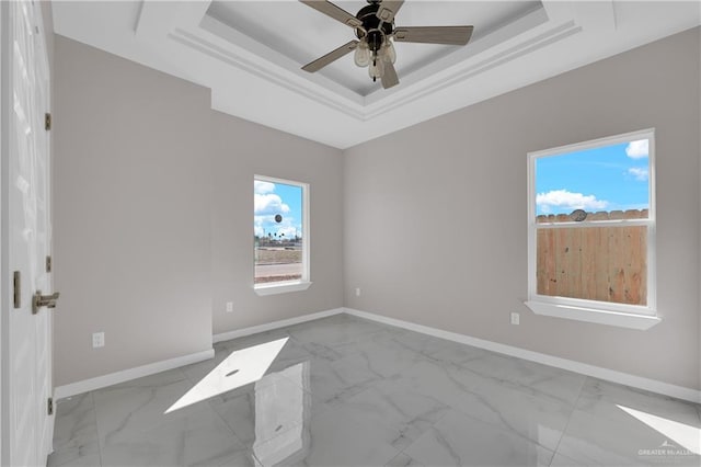 unfurnished room with marble finish floor, baseboards, and a raised ceiling