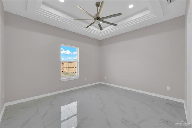 empty room featuring marble finish floor, baseboards, and a tray ceiling