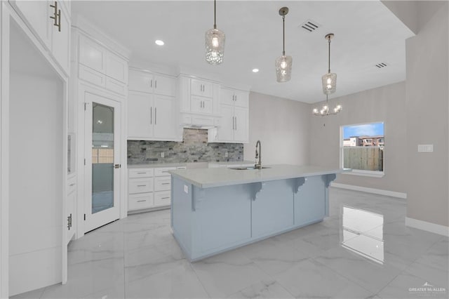 kitchen featuring marble finish floor, light countertops, visible vents, backsplash, and a sink