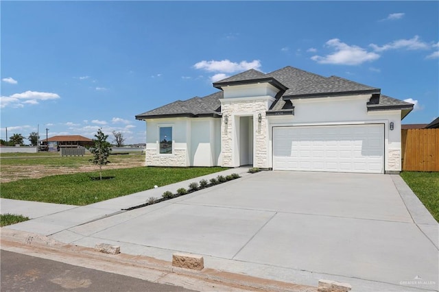 view of front of property with concrete driveway, a front lawn, stone siding, an attached garage, and stucco siding