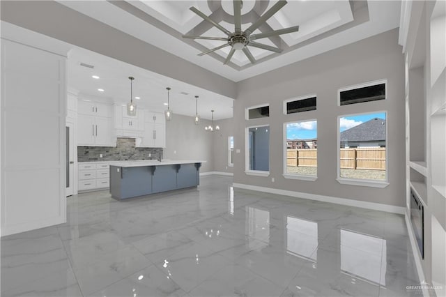 kitchen with marble finish floor, a kitchen bar, open floor plan, white cabinetry, and baseboards