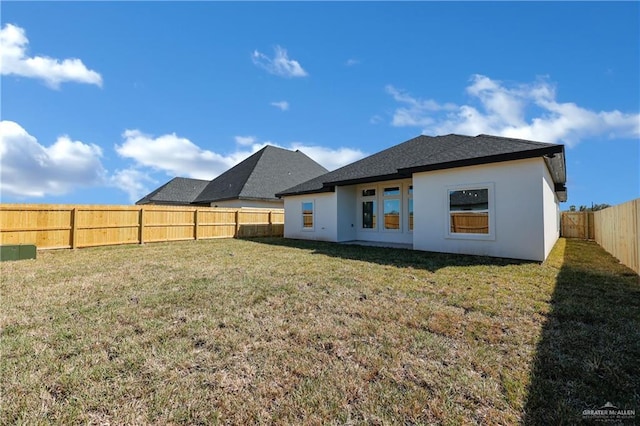 rear view of property featuring a lawn, a fenced backyard, and stucco siding