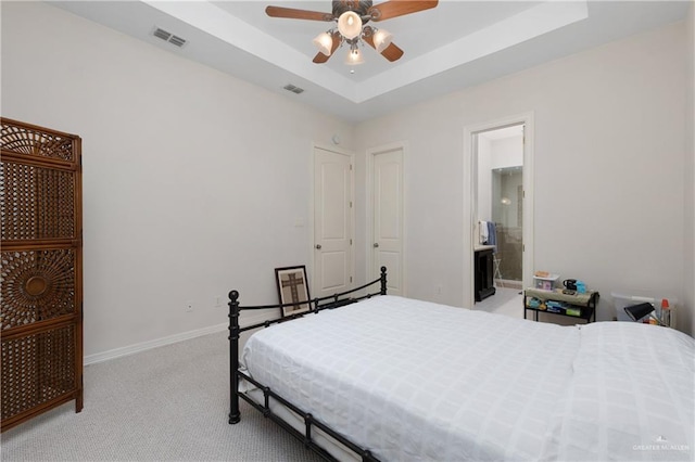 bedroom featuring ceiling fan, light colored carpet, connected bathroom, and a raised ceiling