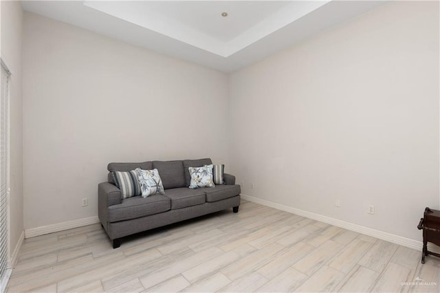 sitting room with a raised ceiling and light wood-type flooring