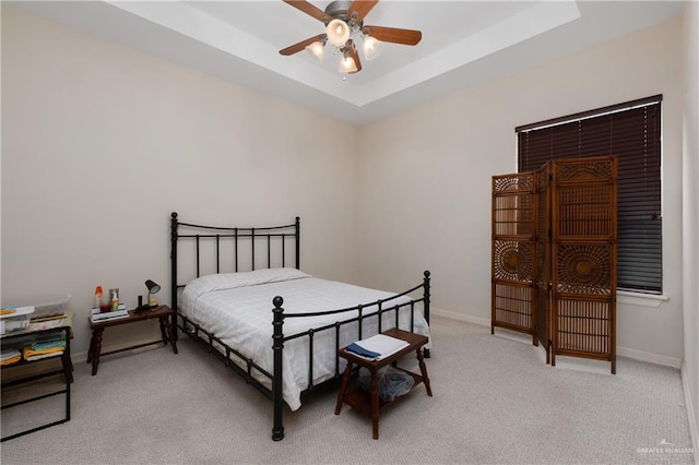 carpeted bedroom featuring ceiling fan and a tray ceiling