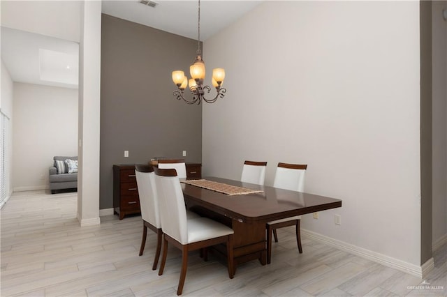 dining space with an inviting chandelier, light hardwood / wood-style flooring, and vaulted ceiling