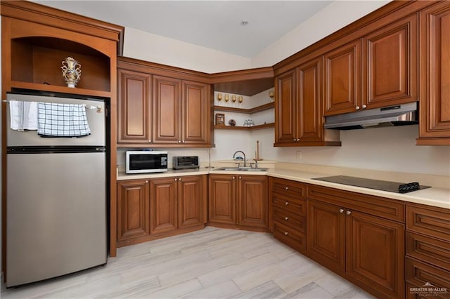 kitchen featuring black electric cooktop, stainless steel fridge, and sink