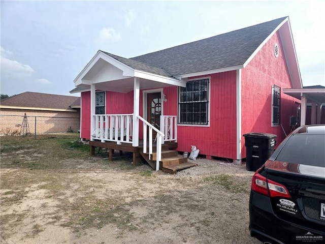 view of front of home featuring fence and roof with shingles