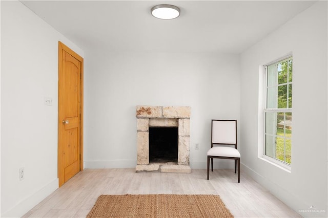 unfurnished room with a fireplace, a healthy amount of sunlight, and light wood-type flooring