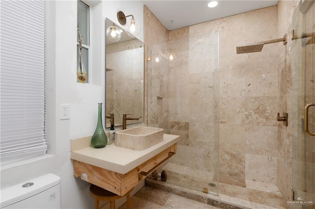 bathroom with toilet, a shower with shower door, and sink