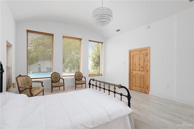 bedroom featuring an inviting chandelier, light hardwood / wood-style floors, and vaulted ceiling