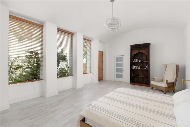 bedroom with a chandelier, light hardwood / wood-style floors, and lofted ceiling