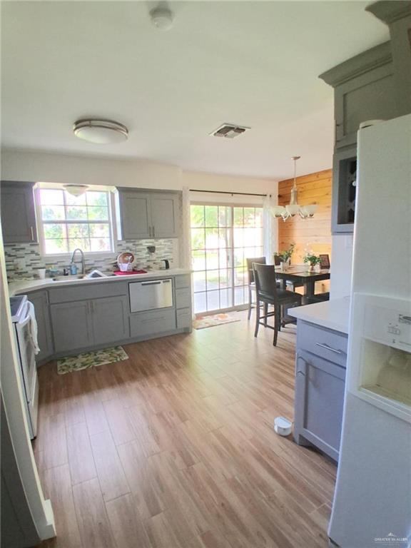 613 W Sprague St, Edinburg, TX 78539 - kitchen featuring white refrigerator with ice dispenser, gray cabinets, a sink, backsplash, and stainless steel dishwasher