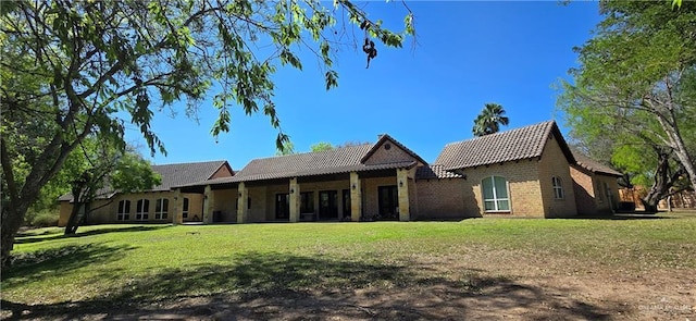 back of house with a lawn and brick siding