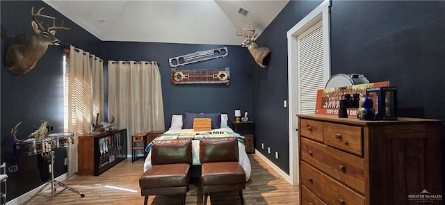 bedroom featuring visible vents, lofted ceiling, baseboards, and wood finished floors