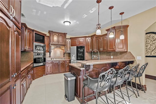 kitchen with pendant lighting, a breakfast bar, light tile patterned floors, tasteful backsplash, and stainless steel appliances