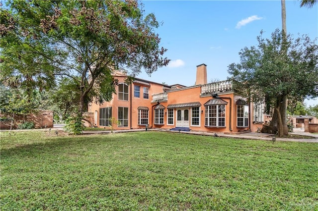 27101 N State Highway 345, San Benito, TX 78586 - back of house featuring stucco siding, a chimney, a yard, and a balcony