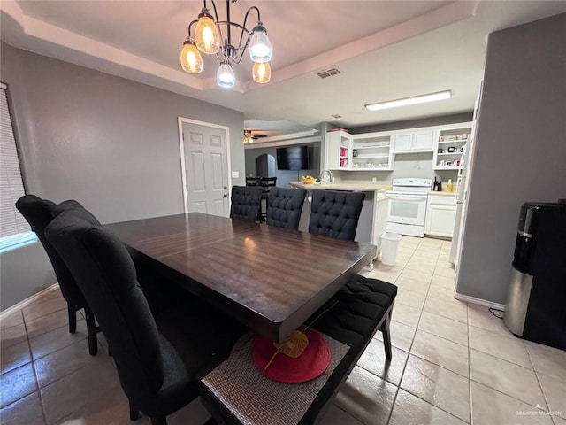 dining room with a tray ceiling, light tile patterned floors, and ceiling fan with notable chandelier