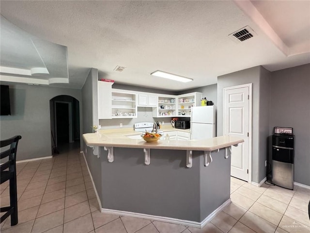 kitchen with white cabinetry, sink, kitchen peninsula, white appliances, and a breakfast bar area