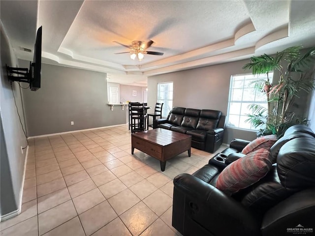 living room with ceiling fan, a healthy amount of sunlight, and a raised ceiling