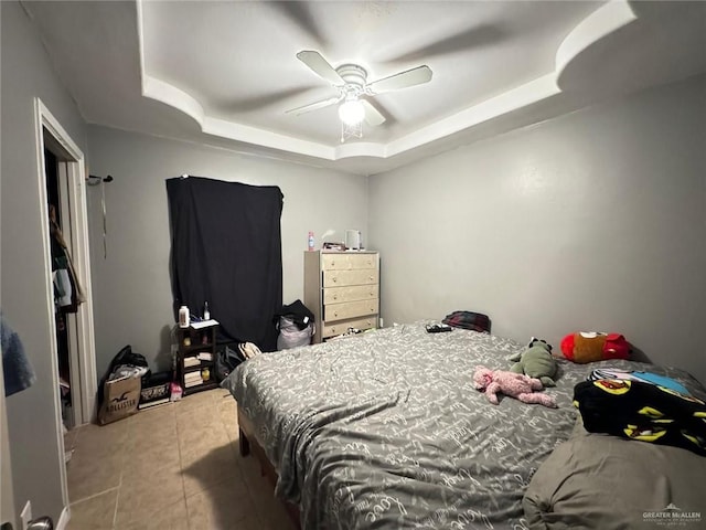 tiled bedroom featuring a tray ceiling and ceiling fan