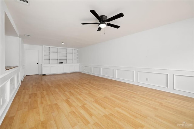 empty room with ceiling fan, light hardwood / wood-style floors, and built in features