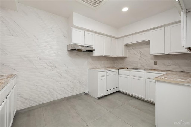 kitchen featuring backsplash, white dishwasher, white cabinets, light tile patterned floors, and range hood