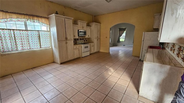3106 E Maren Dr E, Mission, TX 78574 - kitchen with white appliances, arched walkways, light tile patterned flooring, tile counters, and a sink