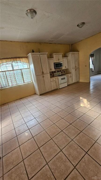 3106 E Maren Dr E, Mission, TX 78574 - kitchen with electric stove, stainless steel microwave, arched walkways, light tile patterned flooring, and cream cabinets