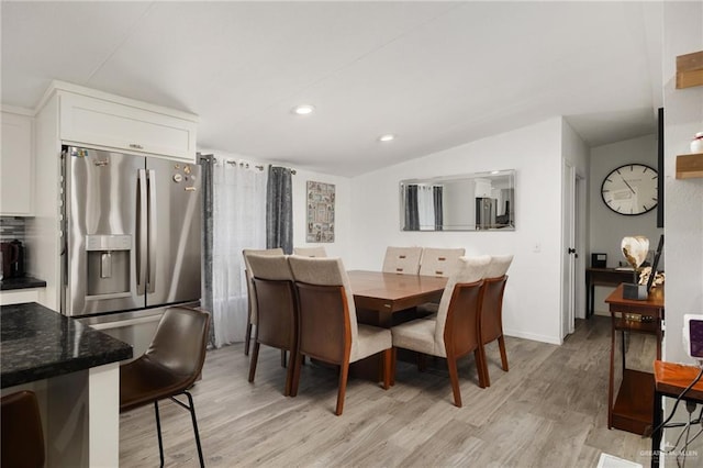 dining space with light wood-type flooring and lofted ceiling