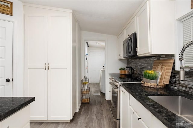 kitchen featuring stainless steel range with electric stovetop, sink, dark stone countertops, white cabinetry, and lofted ceiling