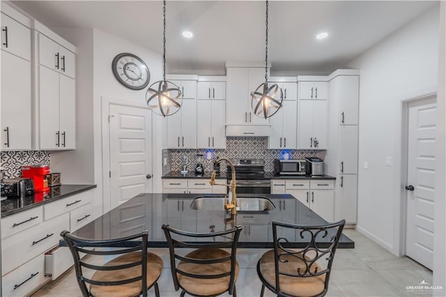 kitchen featuring stainless steel appliances, dark countertops, hanging light fixtures, premium range hood, and a kitchen breakfast bar