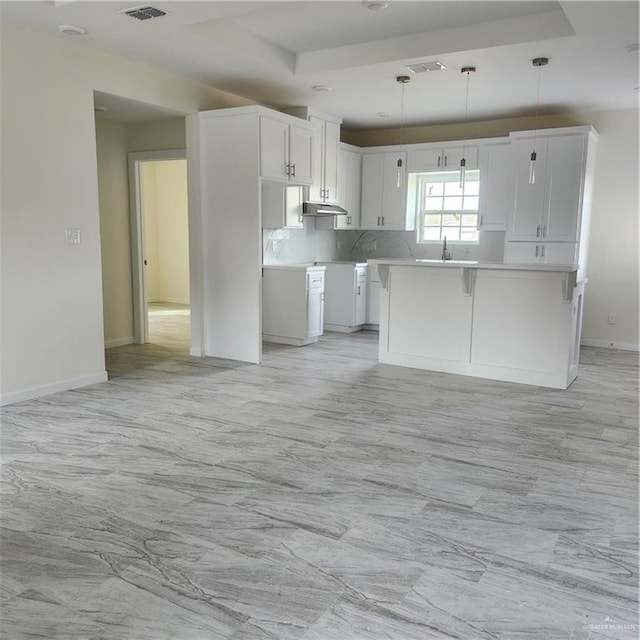 kitchen with white cabinetry, tasteful backsplash, a center island, and hanging light fixtures