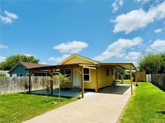 view of front of house featuring a carport, a front yard, concrete driveway, and fence private yard