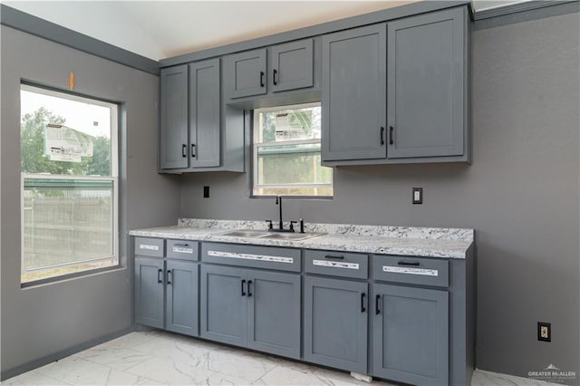 kitchen featuring marble finish floor, gray cabinets, and a sink