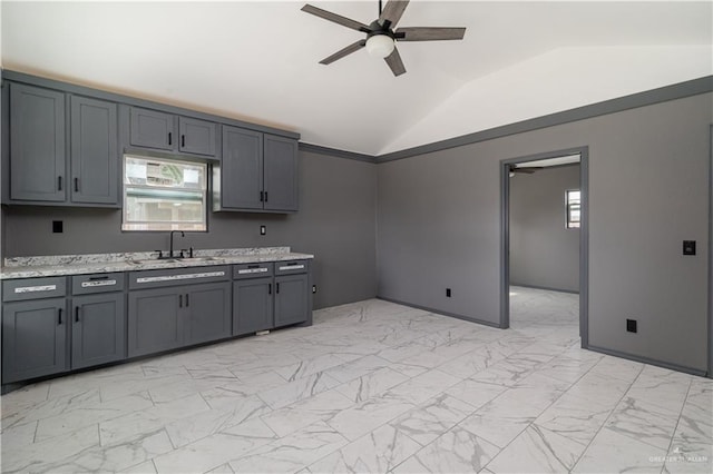 kitchen with a ceiling fan, marble finish floor, vaulted ceiling, gray cabinetry, and a sink