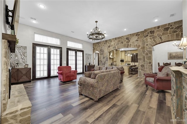 living area featuring recessed lighting, arched walkways, an inviting chandelier, and wood finished floors